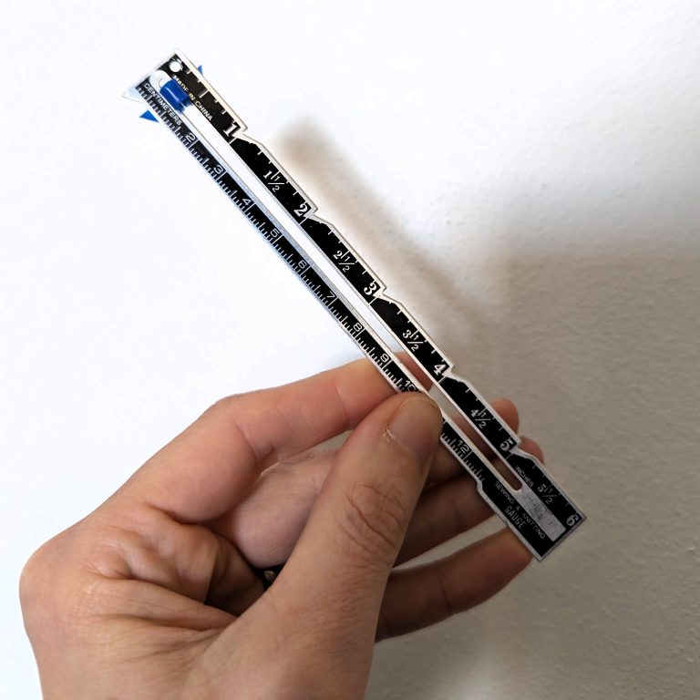 hand holding a small sewing gauge or caliper