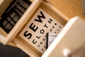 a sewing box with needles and a card reading 'sew cloth toegther'